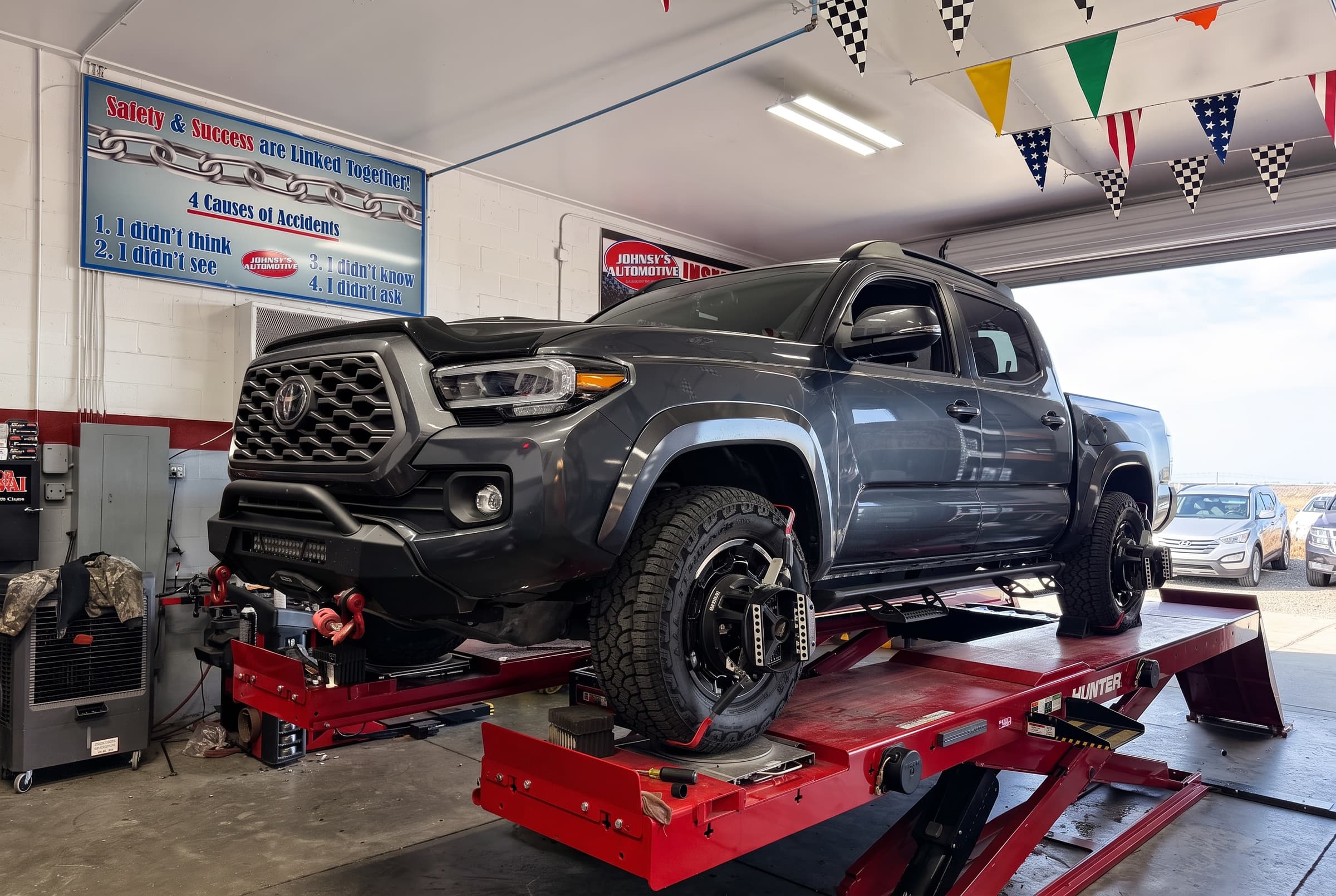 Pickup truck on the alignment rack at Johnny's Automotive with an alignment target on the front wheel