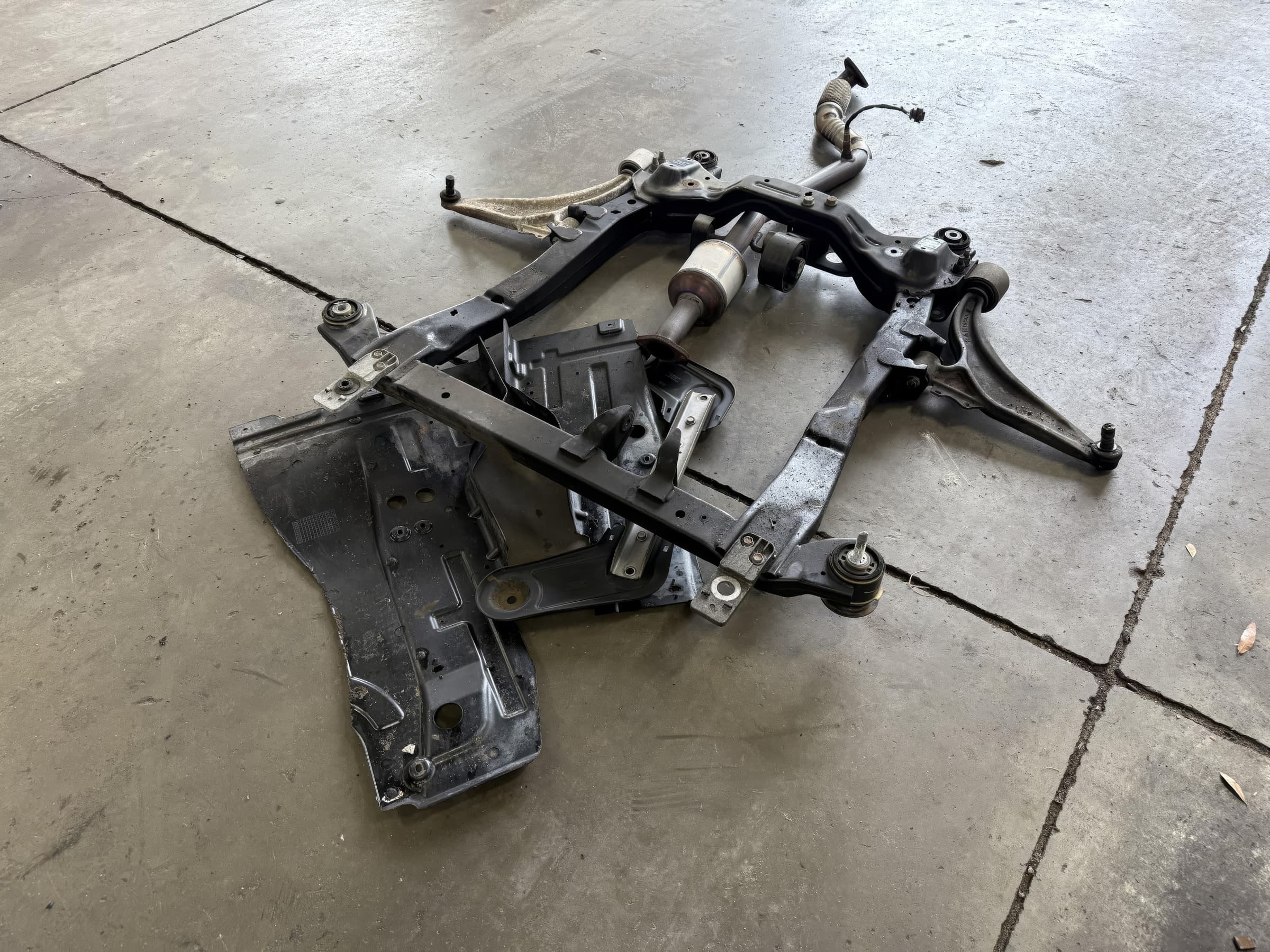 Front subframe with control arms removed and set on the shop floor at Johnny's Automotive